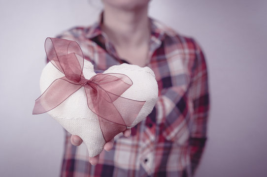 Woman in plaid shirt holding a fabric heart. Valentine's day