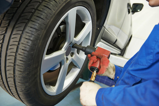 auto mechanic screwing car wheel