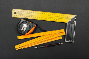 Measuring tools and pencil on black