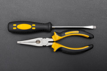 Pliers and screwdriver on black