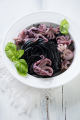 Glass plate with black tagliatelle and octopuses, close-up