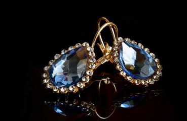 Earrings from gold against a dark background. © serg6legion