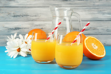 Glass of orange juice with slices, flowers and straws