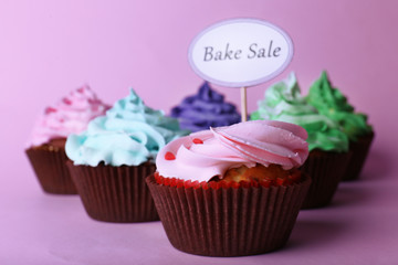 Delicious cupcakes with inscription on color background