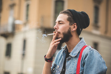 young handsome bearded hipster man smoking cigarette - obrazy, fototapety, plakaty