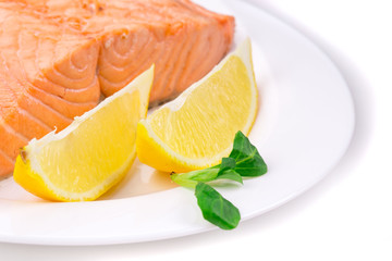Fried salmon fillet on plate with lemon.