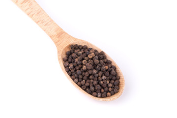 Black peppercorns on a wooden spoon.