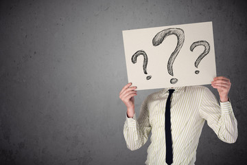Businessman holding a paper with question marks in front of his