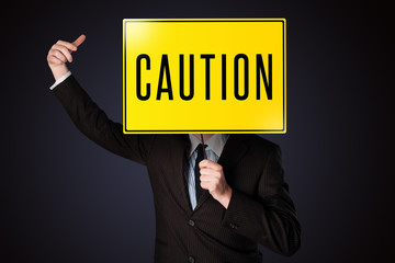 Businessman holding a caution sign