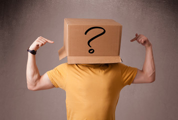 Young man gesturing with a cardboard box on his head with questi