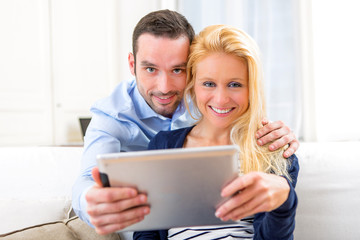 Young attractive couple having fun using tablet