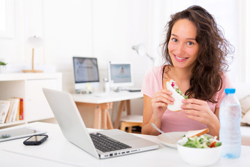 Fototapeta na wymiar Young attractive student eating sandwich while working