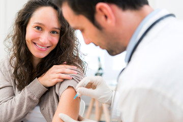 Young attractive woman being vaccinated - obrazy, fototapety, plakaty