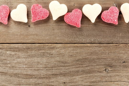 Heart shaped Valentines Day candy border on wooden background