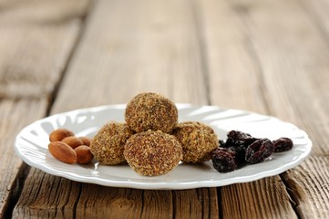 Homemade almond candies on white plate with almond and raisins