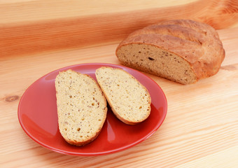 Two slices of bread on a red plate, with a loaf of bread