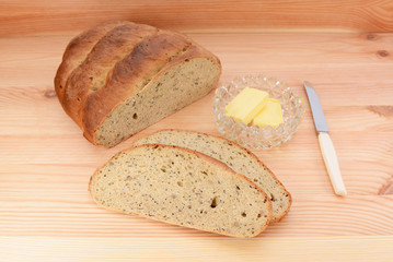 Fresh bread with butter and knife on a wooden table