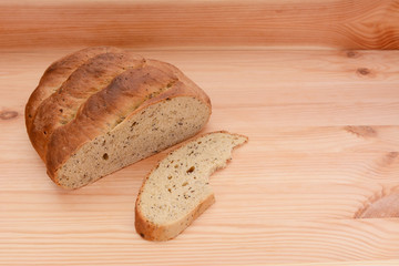 Half-eaten loaf of bread on a table with a cut slice