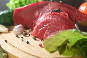 Raw beef meat with vegetables on wooden table