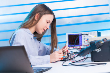 Girl repairing electronic device on the circuit board
