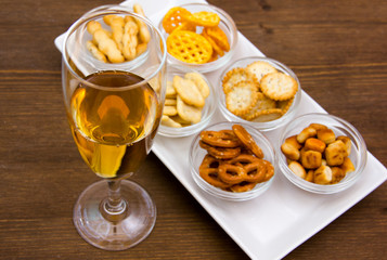 Flute with aperitif and pretzels on wooden table