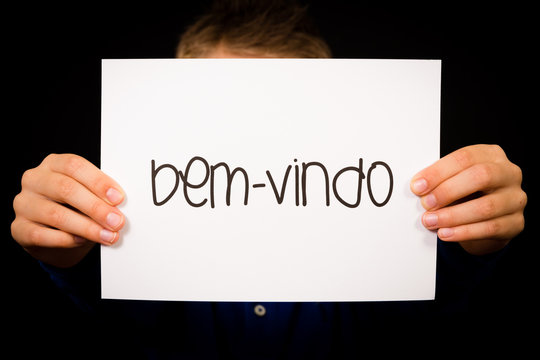 Child holding sign with Portuguese word Bem-vindo - Welcome