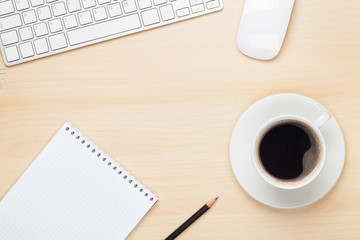 Office table with notepad, computer and coffee cup