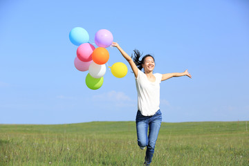 young asian woman on green grassland with colored balloons 