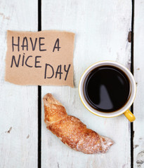 Composition of coffee, fresh croissant and paper card