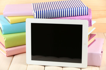 PC tablet and books on wooden table, on wooden background