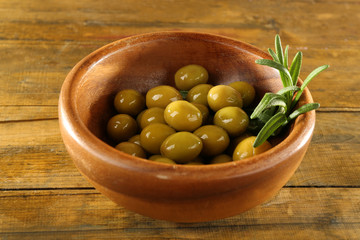 Green olives in the round bowl with branch