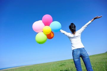 young asian woman on green grassland with colored balloons 