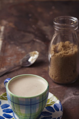 Cute coffee cup and raw sugar in glass bottle