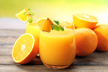 Glass of orange juice and slices on wooden table background