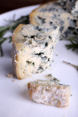 Blue cheese with sprigs of rosemary on plate, closeup view