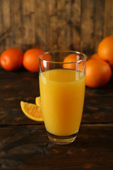 Glass of orange juice with slices on wooden table background