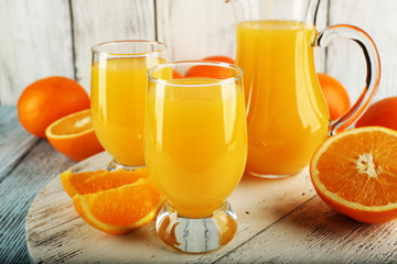 Naklejka na ściany i meble Glass of orange juice with slices on color wooden background