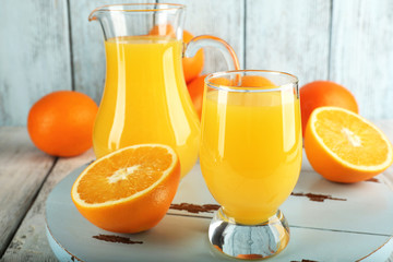 Obraz na płótnie Canvas Glass of orange juice with slices on color wooden background