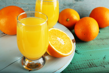 Glass of orange juice with slices on color wooden background