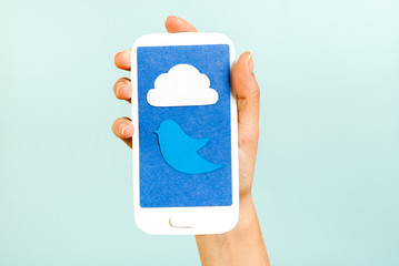 Conceptual phone showing a cloud and bluebird on blue background - obrazy, fototapety, plakaty