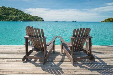 Two beach chairs placed on wooden floor at the sea view
