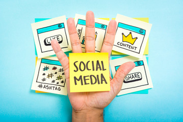 Sticky note with social media on hand with blue background.