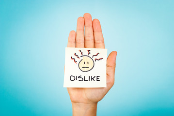Dislike emoticon note on hand with blue background