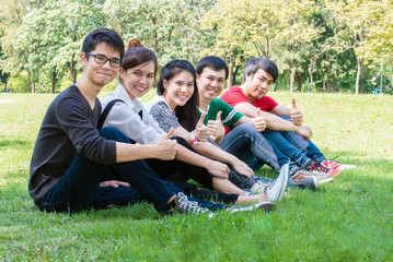 Group of student gesturing thumb up while sitting on campus