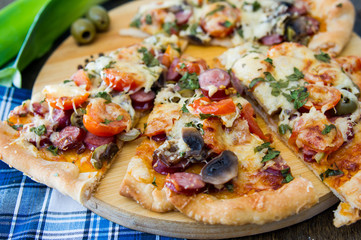 chopped pieces of pizza with mushrooms, olives and salami