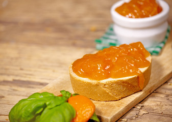Fototapeta na wymiar Tangerine jam with slice of bread on wooden table