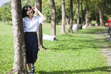 Girl standing and smiling near a tree.