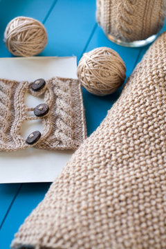 Soft knitted blanket, yarn balls lying on blue background