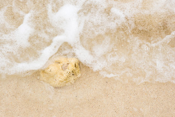 Fototapeta na wymiar White wave of the sea on the sand beach
