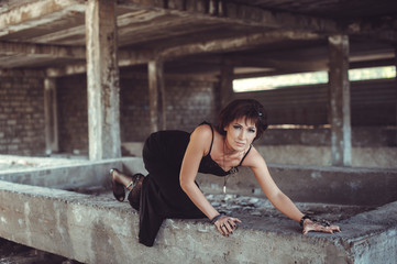 Fototapeta na wymiar Beautiful woman in black dress in abandon building